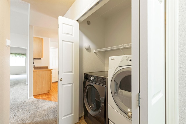 clothes washing area featuring light carpet, washing machine and dryer, and laundry area