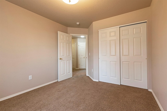 unfurnished bedroom with a closet, baseboards, carpet, and a textured ceiling