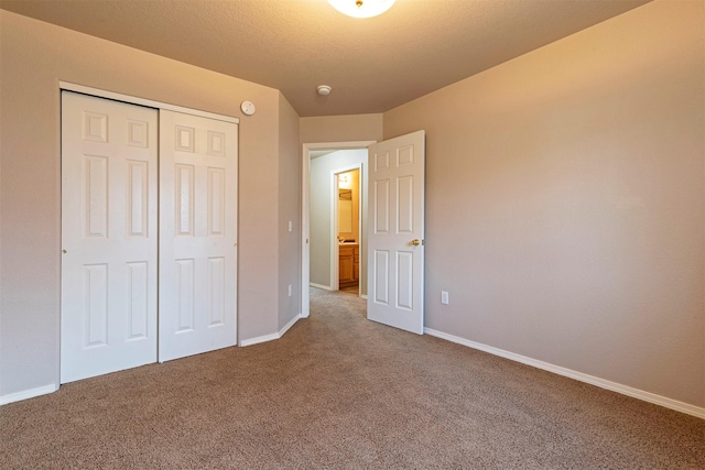 unfurnished bedroom featuring baseboards, a closet, carpet floors, and a textured ceiling