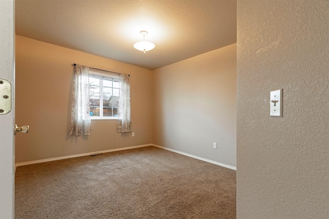 unfurnished room with carpet flooring, visible vents, baseboards, and a textured ceiling