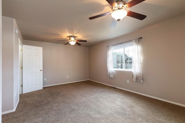 carpeted empty room with visible vents, baseboards, and ceiling fan