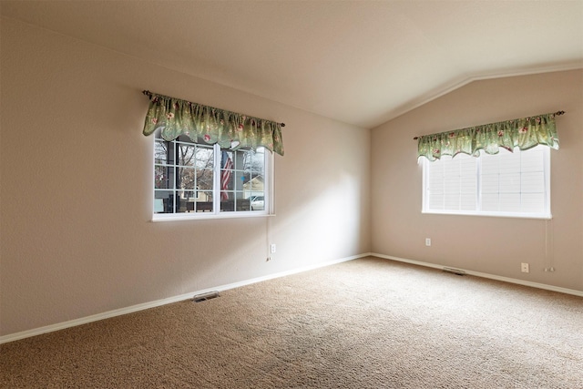 carpeted spare room with visible vents, baseboards, and vaulted ceiling