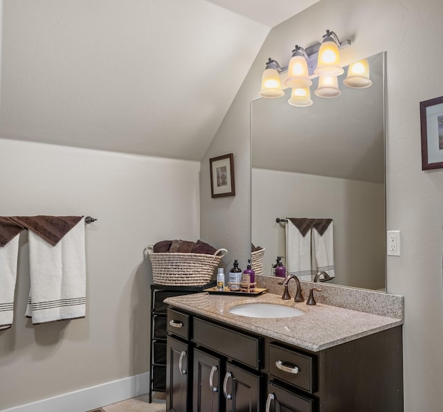 bathroom featuring baseboards, vanity, and lofted ceiling