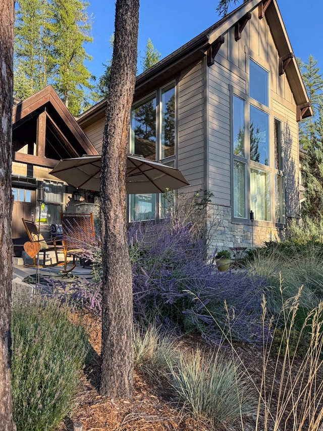 view of side of property featuring stone siding, board and batten siding, and a patio area