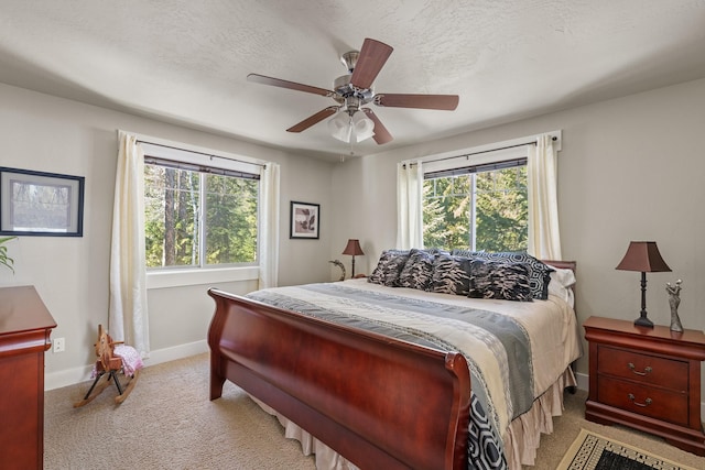 bedroom with multiple windows, light colored carpet, baseboards, and a textured ceiling