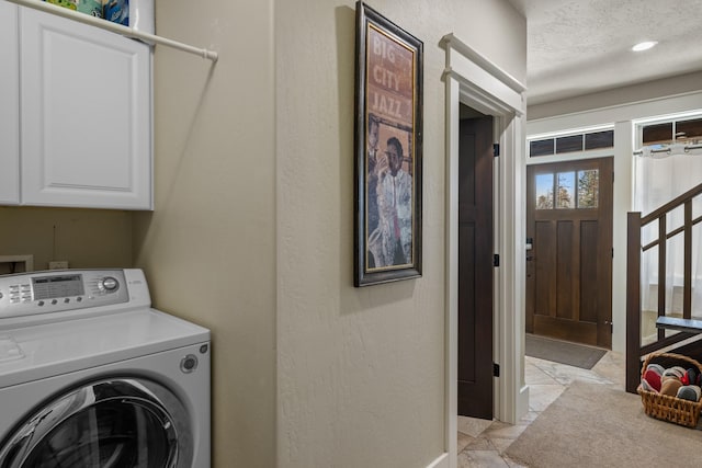 laundry room with cabinet space, a textured ceiling, and washer / dryer