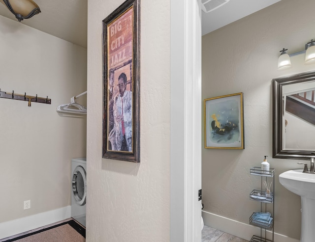 washroom with visible vents, baseboards, laundry area, washer / clothes dryer, and a sink