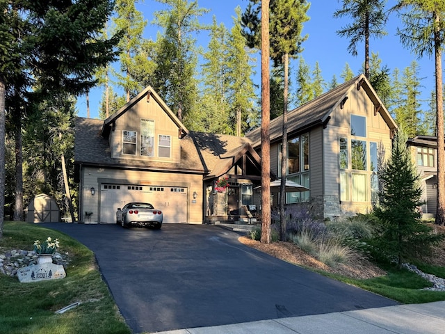 view of front of property featuring board and batten siding, roof with shingles, a garage, stone siding, and driveway