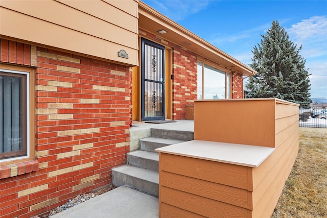 property entrance with brick siding and fence