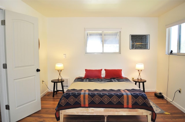 bedroom with visible vents, baseboards, and wood finished floors