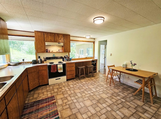 kitchen with under cabinet range hood, a healthy amount of sunlight, white electric range, and open shelves