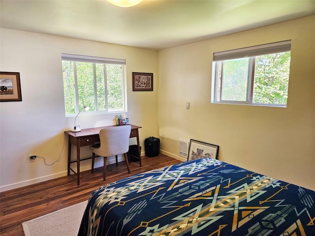 bedroom with visible vents, multiple windows, wood finished floors, and baseboards