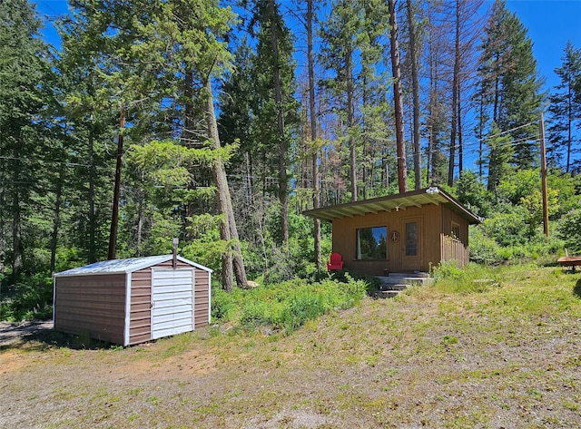 view of outbuilding with an outbuilding and a forest view