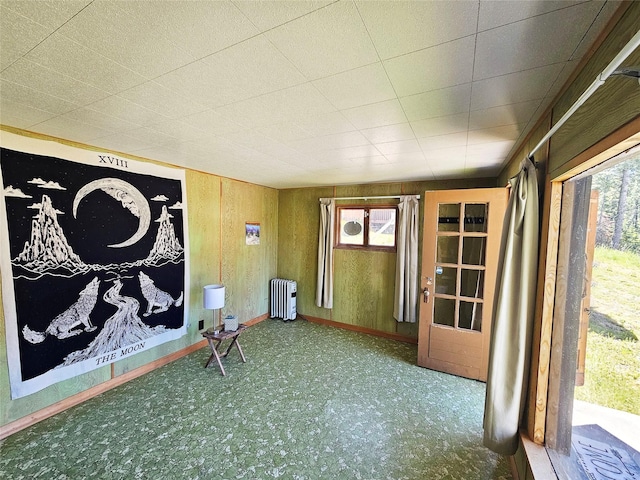 interior space with wood walls, radiator, and baseboards