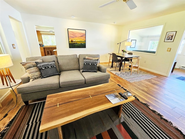 living area with a healthy amount of sunlight, baseboards, a ceiling fan, and wood finished floors