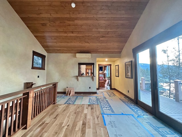 interior space with baseboards, lofted ceiling, a wall unit AC, wooden ceiling, and wood finished floors