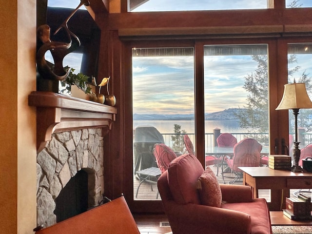 living room featuring a stone fireplace, a water view, and a wealth of natural light