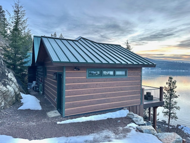 exterior space with a standing seam roof, a water view, and metal roof