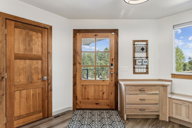 doorway to outside with visible vents, wood finished floors, and baseboards