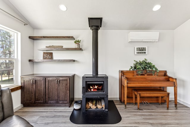 interior space with baseboards, a wall mounted air conditioner, recessed lighting, a wood stove, and wood finished floors