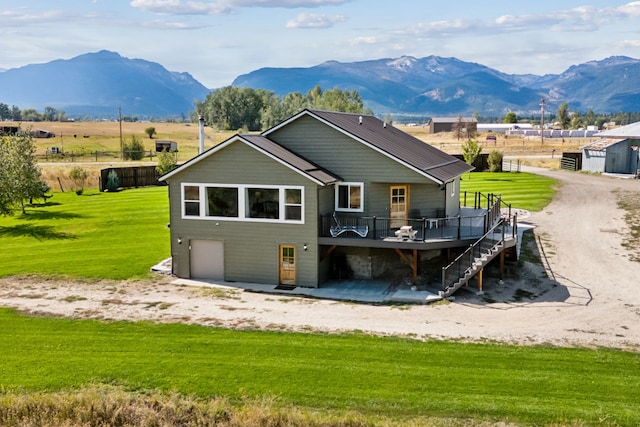 back of house featuring a lawn, a deck with mountain view, stairway, metal roof, and a garage