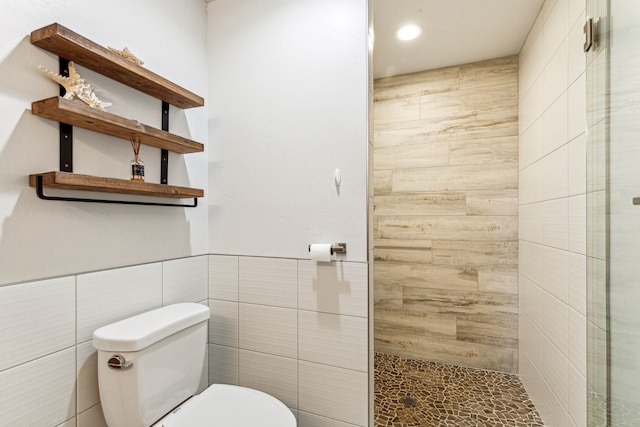 bathroom featuring recessed lighting, toilet, tile walls, and a stall shower