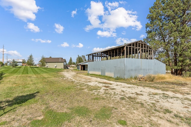 view of yard with dirt driveway, an outbuilding, and a pole building