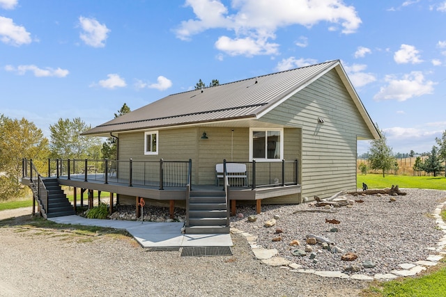 back of property with stairs, a wooden deck, and metal roof