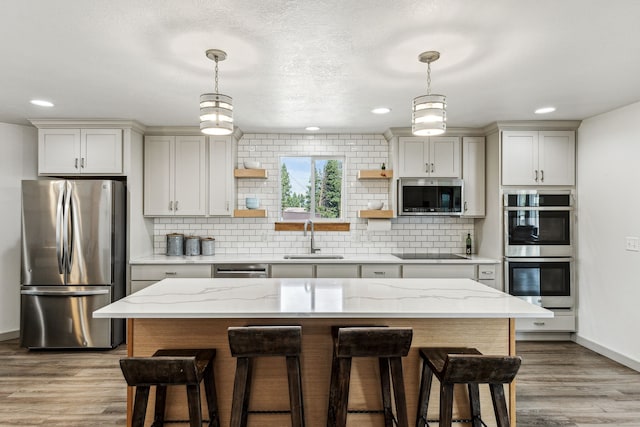 kitchen featuring a sink, backsplash, a kitchen breakfast bar, stainless steel appliances, and open shelves