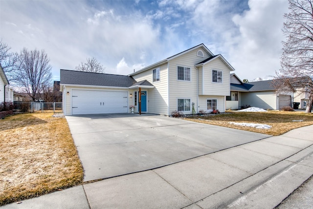 tri-level home with a garage, roof with shingles, driveway, and fence