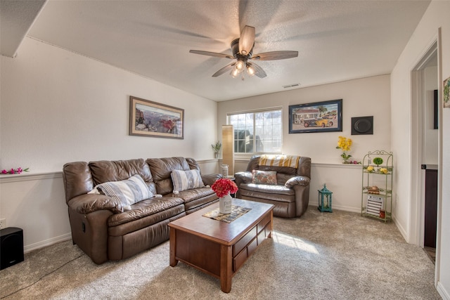 living area with light carpet, visible vents, baseboards, and a ceiling fan