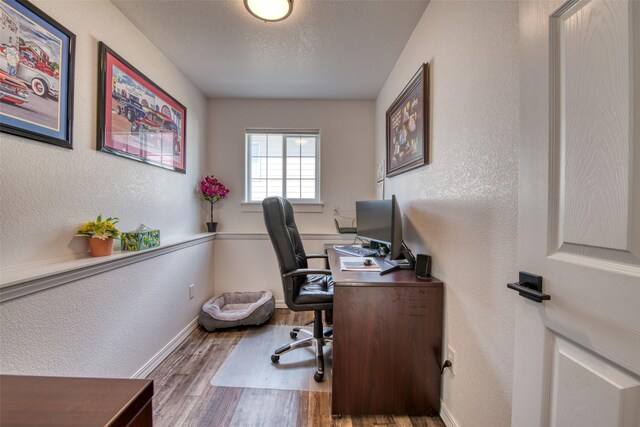 office featuring baseboards, a textured ceiling, a textured wall, and wood finished floors