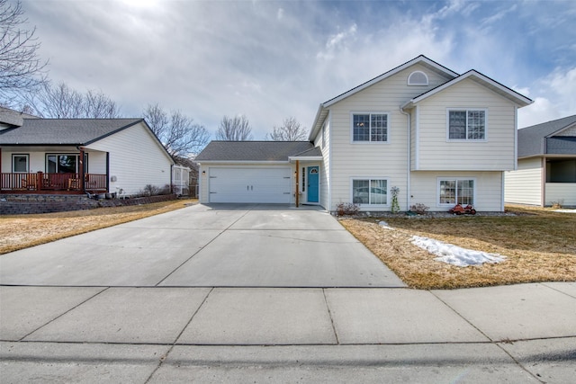 split level home with a porch, concrete driveway, and an attached garage