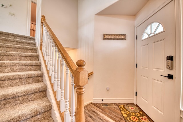 entryway with stairway, baseboards, visible vents, and wood finished floors