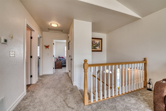 hallway with baseboards, an upstairs landing, and carpet