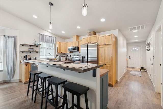 278 Empire Loop, Kalispell, MT 59901 - kitchen with stainless steel appliances, light brown cabinets, a kitchen breakfast bar, light wood-style flooring, and a center island