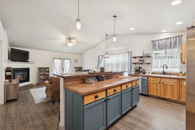 278 Empire Loop, Kalispell, MT 59901 - kitchen featuring dishwasher, vaulted ceiling, wood finished floors, a sink, and a glass covered fireplace