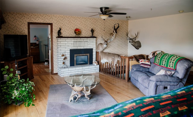 3676 Silverthorn Dr, Stevensville, MT 59870 - living area with wallpapered walls, a ceiling fan, wood finished floors, and a fireplace
