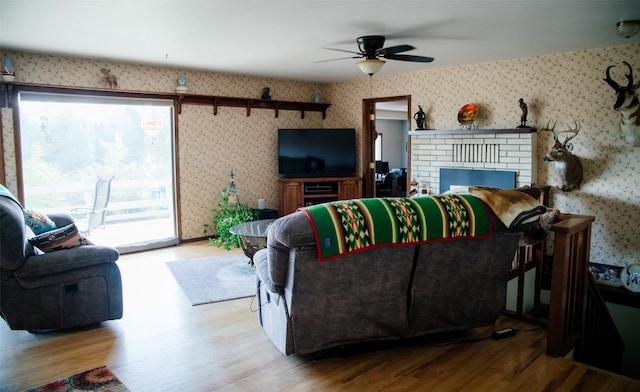 3676 Silverthorn Dr, Stevensville, MT 59870 - living area with wallpapered walls, wood finished floors, a ceiling fan, and a fireplace
