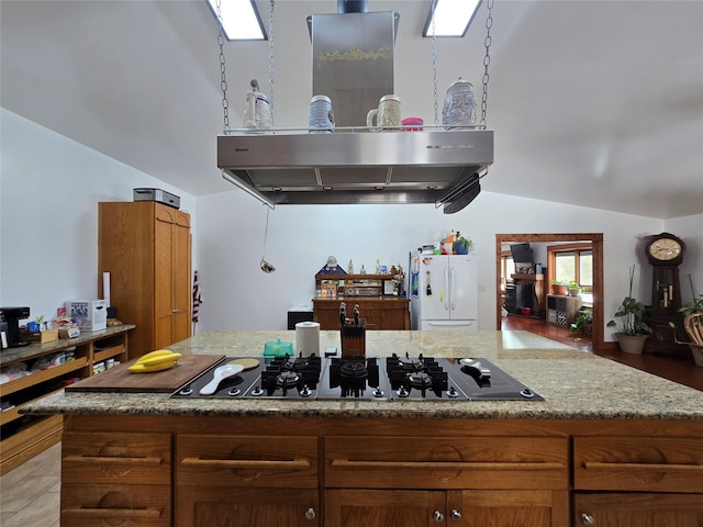 611 S Canyon Dr, Seeley Lake, MT 59868 - kitchen featuring freestanding refrigerator, vaulted ceiling, black gas cooktop, a center island, and light stone countertops