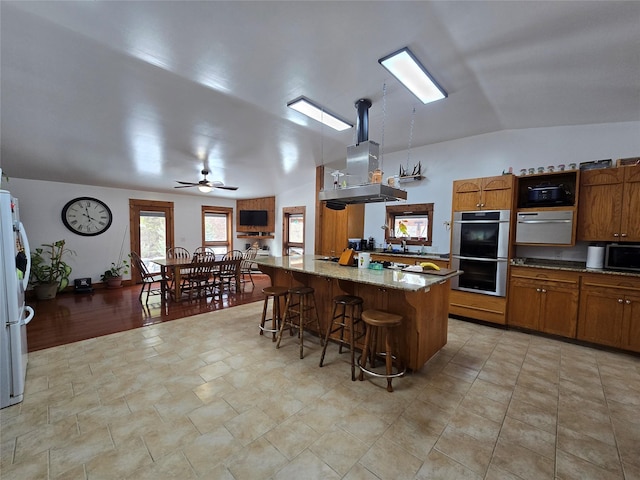 611 S Canyon Dr, Seeley Lake, MT 59868 - kitchen featuring appliances with stainless steel finishes, brown cabinetry, lofted ceiling, a breakfast bar, and light stone countertops