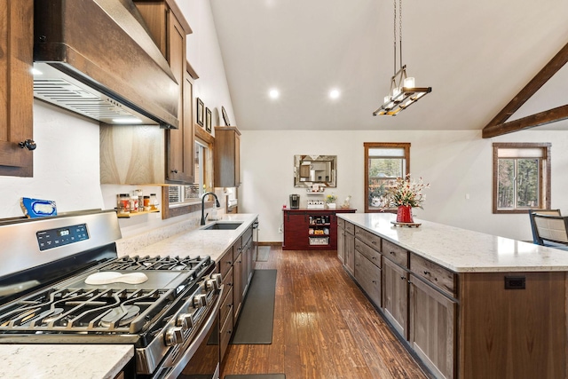 378 Skookum Rd, Lakeside, MT 59922 - kitchen featuring stainless steel range with gas stovetop, wall chimney exhaust hood, vaulted ceiling, a sink, and a center island