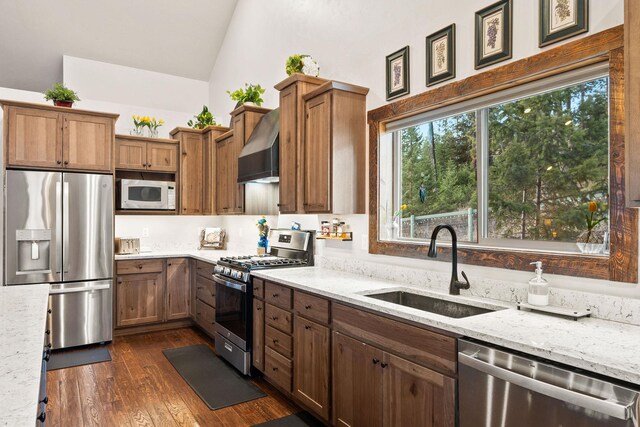 378 Skookum Rd, Lakeside, MT 59922 - kitchen featuring stainless steel appliances, a sink, wall chimney exhaust hood, light stone countertops, and lofted ceiling