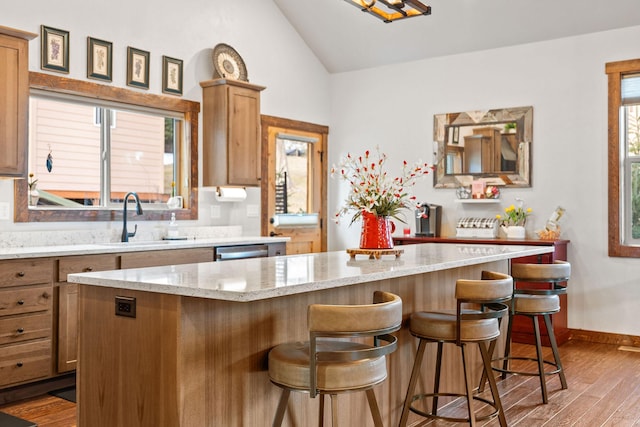 378 Skookum Rd, Lakeside, MT 59922 - kitchen with wood finished floors, vaulted ceiling, a sink, a breakfast bar, and a kitchen island