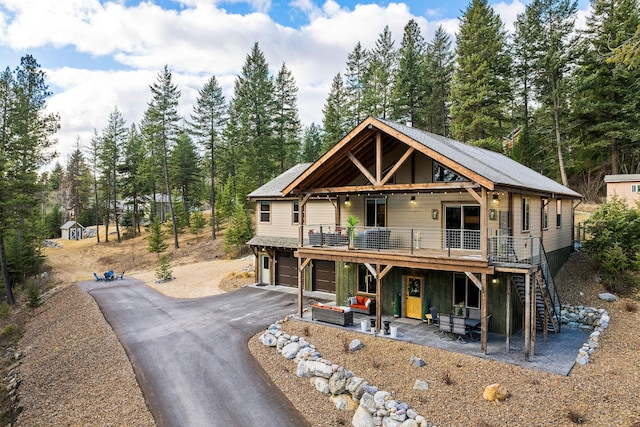 378 Skookum Rd, Lakeside, MT 59922 - view of front of home with an attached garage, asphalt driveway, a deck, stairs, and a patio