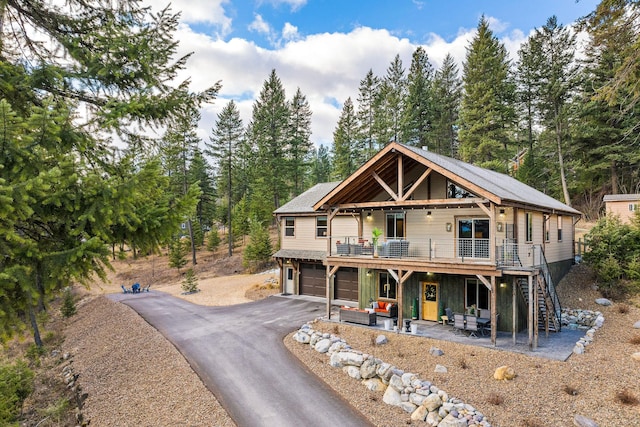 378 Skookum Rd, Lakeside, MT 59922 - view of front of home featuring a garage, asphalt driveway, stairway, a wooden deck, and a patio area