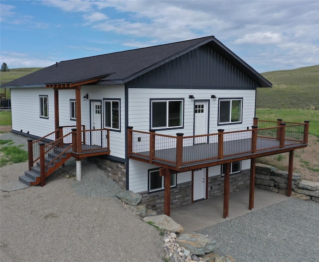 3805 US Highway 93 N, Eureka, MT 59917 - view of front of house featuring a shingled roof, a patio area, stone siding, and a wooden deck
