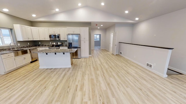 3805 US Highway 93 N, Eureka, MT 59917 - kitchen featuring appliances with stainless steel finishes, a center island, white cabinets, plenty of natural light, and vaulted ceiling