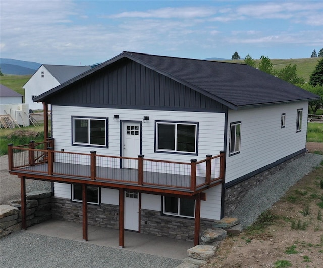3805 US Highway 93 N, Eureka, MT 59917 - view of front facade with a wooden deck, a patio, a shingled roof, and stone siding