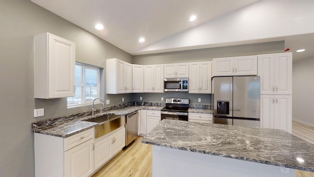 3805 US Highway 93 N, Eureka, MT 59917 - kitchen with stainless steel appliances, vaulted ceiling, dark stone counters, white cabinetry, and light wood-style floors